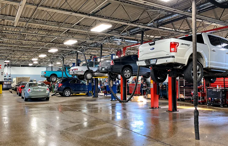 Inside the shop: service bays with cars and a pickup truck up on lifts